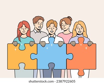 Friendly team of men and women hold giant puzzle pieces symbolizing working together to solve business problems. Business people with smile doing teamwork to increase company income