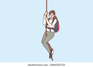 Frightened woman climber hangs on rope and opens mouth from fear, or release of adrenaline in body. Girl engages in extreme sports and is fond of hiking for sake of adrenaline hormone.