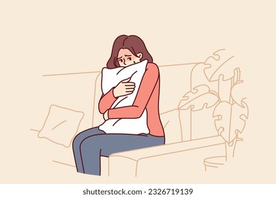 Frightened woman hugging pillow sitting on couch feeling fear and depressed psychological state. Frightened teen girl is afraid to be alone and sad because of breaking up with boyfriend