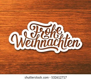 Frohe Weihnachten deutsch text on white paper label with hand lettering over wooden background. Merry Christmas sticker or greeting card vector design template with german inscription