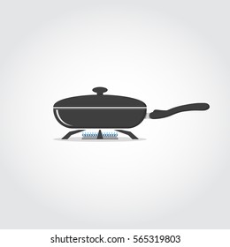 Frying black pan on stove with blue gas flame.