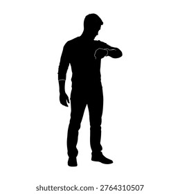 Full length black silhouette of a young man standing and looking at his wrist watch. Isolated vector illustration on a white background.