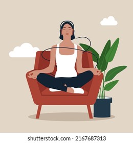 Full length mindful young woman making mudra gesture, sitting in lotus position on comfortable couch at home. Peaceful millennial girl deeply meditating, doing breathing yoga exercises alone.