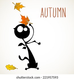 Funny black cat surprised by autumn falling leaves, room for your text.