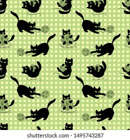 Funny black kittens playing with clews. Seamless pattern on green checked background, vector.