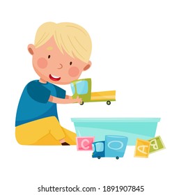 Niño gracioso sentado en el suelo y jugando con diferentes juguetes en la ilustración del vector del salón de juegos