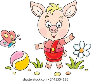 Funny cartoony little piglet playing with its ball and merry butterfly on a green summer lawn, vector cartoon illustration on a white background