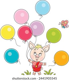 Funny cartoony little piglet playing with colorful toy balloons and merry butterfly on a green summer lawn in a park, vector cartoon illustration on a white background