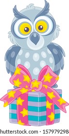 Funny grey owl sitting on a decorated box of a holiday gift, vector cartoon illustration on a white background