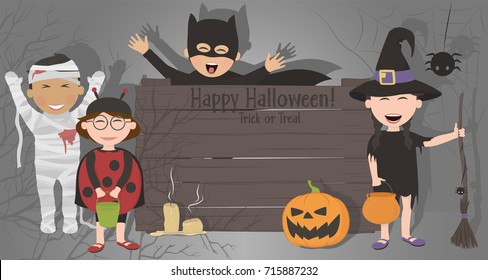 Funny kids in costumes celebrate Halloween. Boys and girls, smiling and holding a blank for your text on the background of ominous shadows.