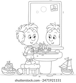 Funny little boy brushing his teeth at a mirror and washbasin in a bathroom with toys, black and white vector cartoon illustration for a coloring book