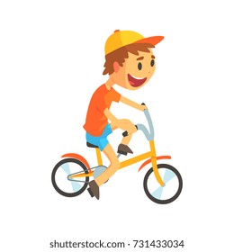 Funny little boy in yellow baseball cap riding bicycle