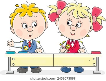 Funny little schoolgirl and schoolboy with their exercise books and pen cases sitting at a desk and talking in a classroom at a lesson in primary school, vector cartoon illustration on white