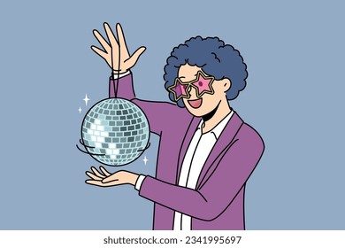 Funny man with disco ball with curly wig on head came to nightclub or dance floor to have fun and relax. Young guy enjoys atmosphere of music festival or disco party for party people