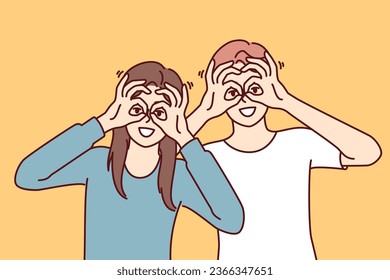 Funny man and woman make binoculars from fingers and look at screen smiling to cheer themselves up or friends. Funny guy and girl bring hands to eyes, demonstrating glasses gesture