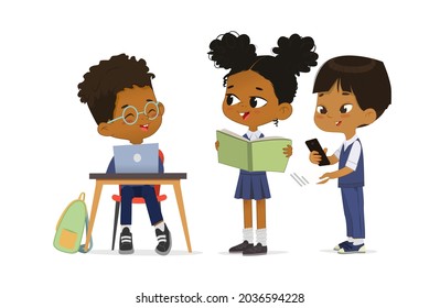 Funny multiracial dark skin primary pupils smiling talking together vector flat illustration. Cute schoolgirl and schoolboy wearing trendy school uniform use book, laptop and smartphone isolated