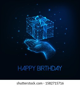 Futuristic happy birthday greeting card with glowing low polygonal human hand holding gift box with ribbon bow isolated on dark blue background. Modern wire frame mesh design vector illustration.