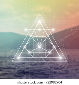 Futuristic vector art with interlocking hipster style triangles and other geometry shapes in front of blurry photo backdrop.