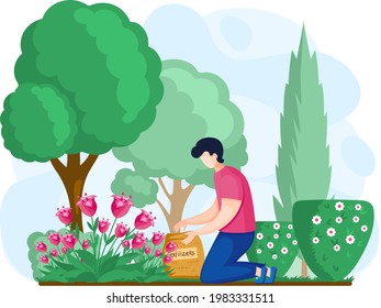 Gardener fertilizes flowers, trees and bushes in garden. Young man cultivates soil and grows plants. Boy is kneeling and holding sack of fertilizer in green park. Guy works on land for agriculture