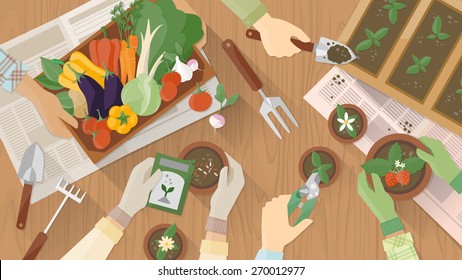 Gardeners hands working together on a wooden table top view with gardening tools, they are planting seeds and plants and carrying a vegetables crate