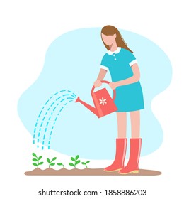 Gardening.  Young woman in her garden waters plants from a watering can.  