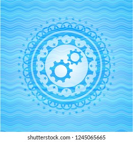 gear, team work icon inside light blue water wave badge.