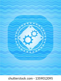 gear, team work icon inside sky blue water wave style emblem.