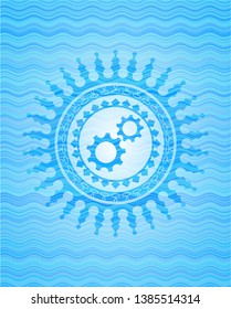gear, team work icon inside sky blue water style badge.