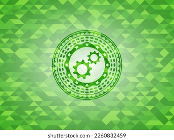 gear, team work icon inside green emblem with triangle mosaic background. 