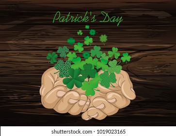 The gesture of the open hands. From the hands of fly sheets clover. Patrick's day. Greeting card. Vector illustration. Empty space for text labels and advertising. On wooden background.