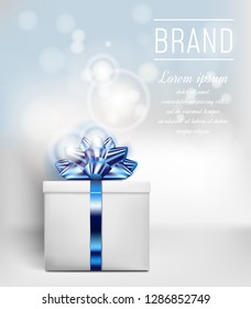 Gift box with blue ribbon and bow on color background with bokeh effect.