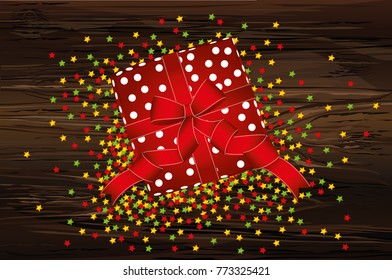 Gift box with bow on Valentine's Day holiday or Birthday. View from above. Confetti is multicolored in the form of stars. Greeting card or invitation on a wooden background.