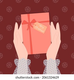 Gift box a Christmas present in female hands, with the inscription Merry Christmas.
