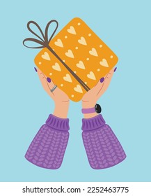 Gift box in hand. A gift wrapped in a festive paper wrapper with a tied bow, ribbon, twine, string. Christmas, Xmas, valentine's day, birthday and New Year present in wrapping paper in hands.