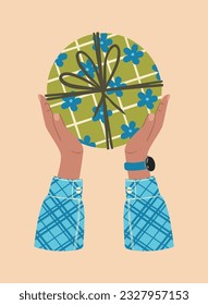 Gift box in hands. A gift wrapped in a festive paper wrapper with a tied bow, ribbon, twine, string. Christmas, Xmas, valentine's day, birthday and New Year present in wrapping paper in hands.