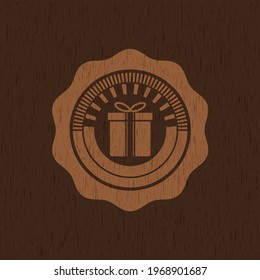 gift box icon inside wood badge or emblem. 