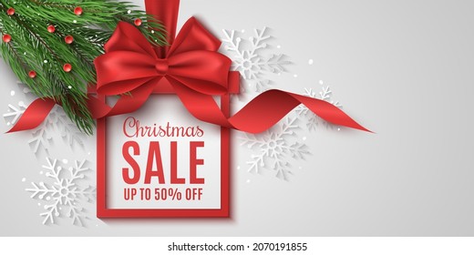 Gift box label for Christmas sale. Realistic red bow with curly ribbon and fir tree. Ad tag. Commercial discount event. Background of paper snowflakes. Vector