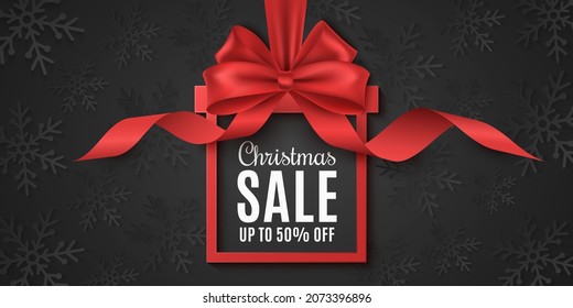 Gift box label for Christmas sale. Realistic red bow with curly ribbon. Ad tag. Template to advertise your business promotions. Commercial discount event. Background of black paper snowflakes. Vector