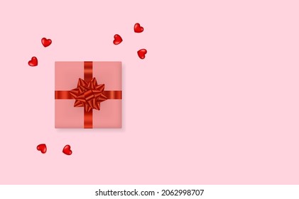 Caja de regalo con arco de cinta roja y corazón sobre fondo rosado. Tarjeta de saludo de vacaciones.