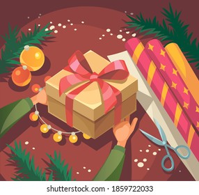 Gift box with red ribbon in the hands. Wrapping packaging presents in stylish paper with ribbon.Top view hands on table with christmas decoration.Making handmade christmas presents.Creative diy hobby.