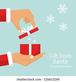 Gift from Santa Claus. Santa Claus holding red gift box in hand, shows open gift. Vector illustration flat design. Merry Christmas and Happy New Year on a snowy background.