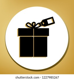 Gift sign with tag. Vector. Black icon with light brown shadow in white circle with shaped ring at golden background.