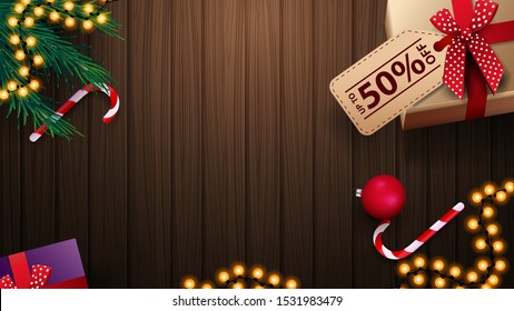 Gift with tag price, candy cane, Christmas tree branch, Christmas ball and garland on wooden table. Background for discount banners