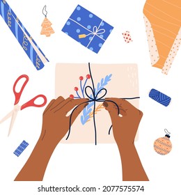 Gift wrapping process with box, scissors and thread from above, flat vector illustration isolated on white background. Christmas or winter holidays presents preparation with human hands.