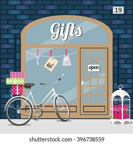 Gifts shop (presents store). Shop facade. Bike with gift boxes and birdcage with flowers. Blue brick building. Vector illustration.