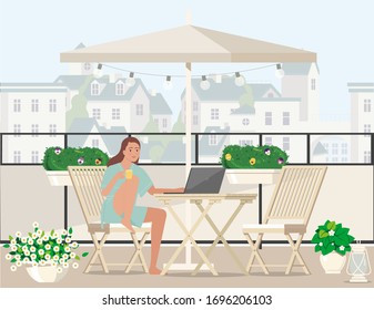 A girl in a bathrobe with a cup of tea works at the computer while sitting on the balcony.