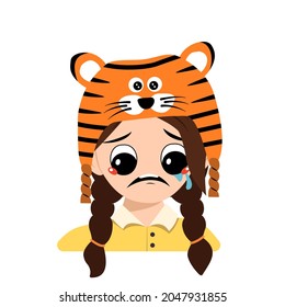 Girl with big eyes and depressive emotion, crying, tears face in tiger hat. Cute kid with sad face in a festive costume for New Year, Christmas and holiday. Head of adorable child with emotions