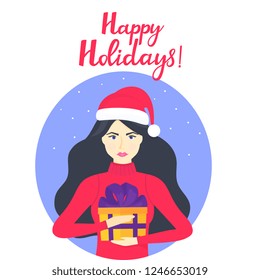 The girl in the cap of Santa Claus and in a warm winter sweater is holding a box with a gift. Happy holidays hand lettering.