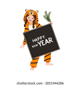 Girl in carnival costume of tiger with sign for text and fir branch in hand. Child in party pyjamas. Kid in jumpsuit or kigurumi, festive clothes for New Year, Christmas or holiday