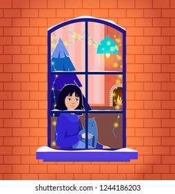 A girl with a cat waiting for Christmas evening near the window decorated with lights. On the background is living room with Christmas tree, fireplace, socks for gifts